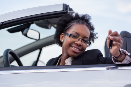 Young beautiful black woman driver holding car keys driving her new carの写真素材