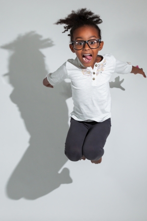 Portrait of cute Young African American girl jumping, over gray backgroundの写真素材