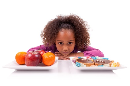 Little African Asian girl hesitating between fruits or  candy,isolated on white backgroundの写真素材