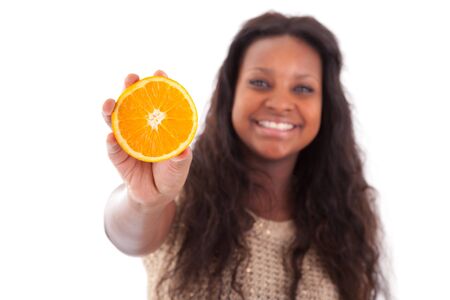 Young African American teenage girl holding a sliced orange, isolated on white backgroundの写真素材
