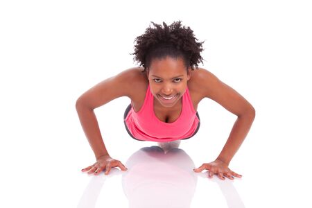 Young beautiful african fitness woman doing push up exercises on floor,isolated on white backgroundの写真素材