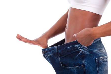 Young african woman in old jeans pant after losing weight. Isolated on white background.の写真素材