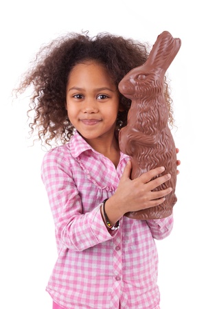 African Asian girl holding a giant chocolate rabbit, isolated on white backgroundの写真素材