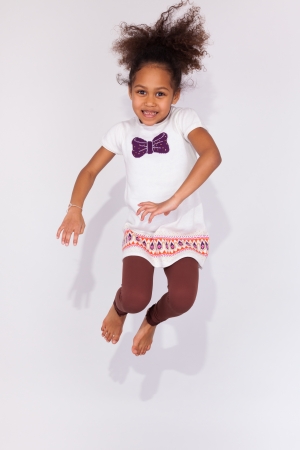 Portrait of cute Young African American girl jumping, over gray backgroundの写真素材