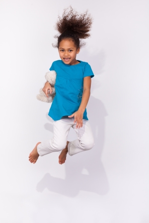 Portrait of cute Young African American girl jumping, over gray backgroundの写真素材
