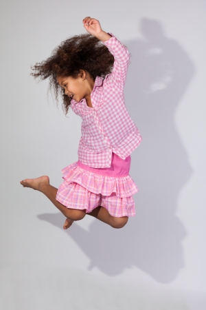 Portrait of cute Young African American girl jumping, over gray backgroundの写真素材