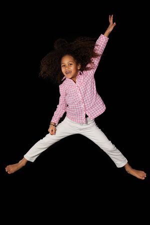 Portrait of cute Young African American girl jumping, over black backgroundの写真素材
