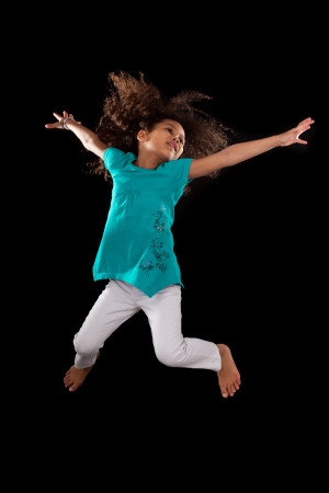 Portrait of cute Young African American girl jumping, over black backgroundの写真素材