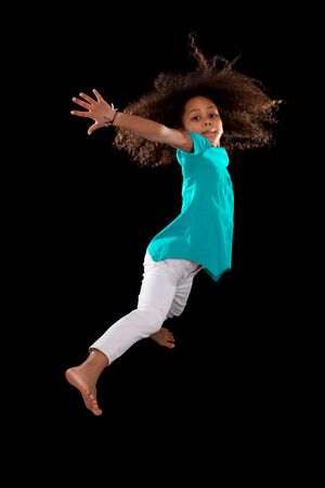 Portrait of cute Young African American girl jumping, over black backgroundの写真素材