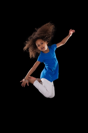 Portrait of cute Young African American girl jumping, over black backgroundの写真素材
