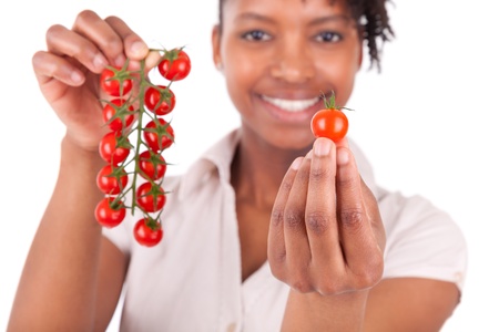 Young happy black / african american woman holding tomatoes, isolated on white backgroundの写真素材