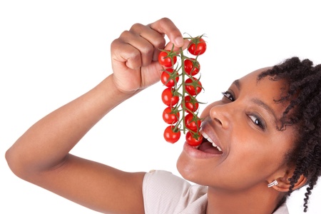 Young happy black / african american woman holding tomatoes, isolated on white backgroundの写真素材