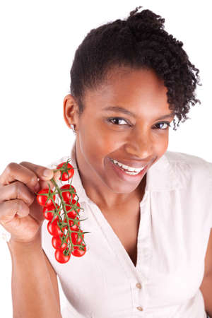 Young happy black / african american woman holding tomatoes, isolated on white backgroundの写真素材