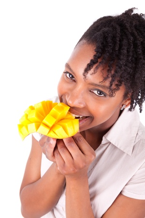 Young happy black / african american woman eating fresh mango isolated on white backgroundの写真素材