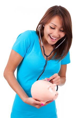 Young happy beautiful asian woman using stethoscope on her piggy bank, isolated on white background - Asian peopleの写真素材