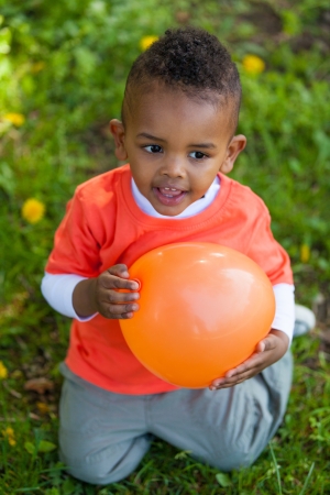 Outdoor portrait of a cute young  little black boy playing with a balloon - African peopleの写真素材
