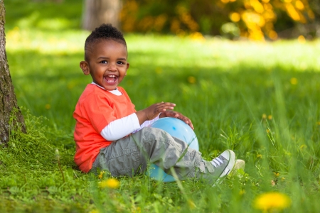 Outdoor portrait of a cute young  little black boy playing with a balloon - African peopleの写真素材