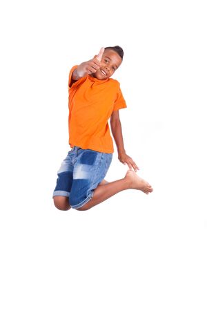 Portrait of a cute teenage black boy jumping over white background - African peopleの写真素材