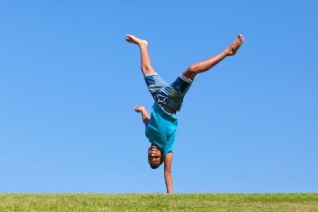 Outdoor portrait of a cute teenage black boy jumping over a blue sky - African peopleの写真素材