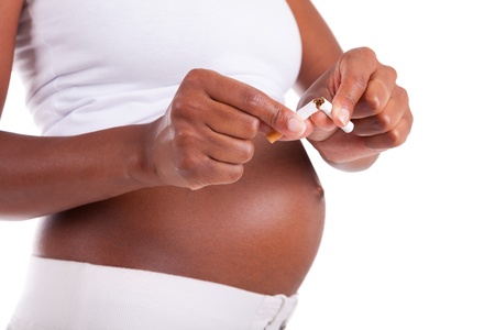 Young pregnant black woman breaking a cigarette , isolated on white background - African peopleの写真素材