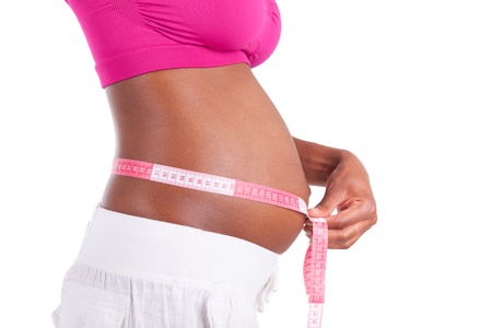 Young pregnant black woman measuring her belly, isolated on white background - African peopleの写真素材