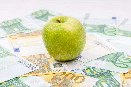 Green apple on Euro banknotes  spreaded over the floor - European currencyの写真素材