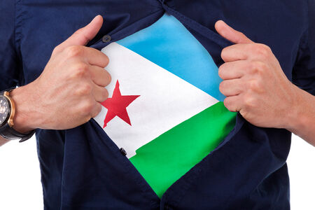 Young sport fan opening his shirt and showing the flag his country Djibouti, Djiboutian flagの写真素材