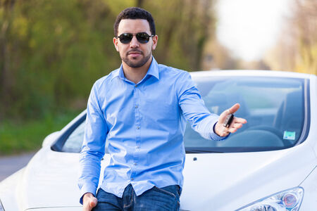 Young latin american driver holding car keys driving his new carの写真素材