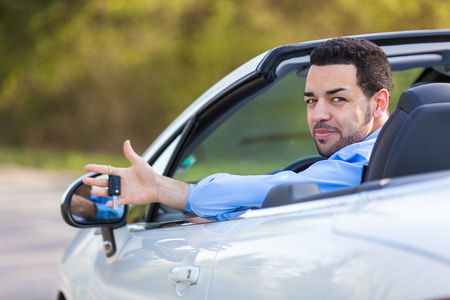 Young black latin american driver holding car keys driving his new carの写真素材
