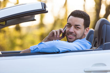 Young latin american driver making a phone call while drivingの写真素材