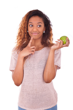 African American young woman holding one green appleの写真素材