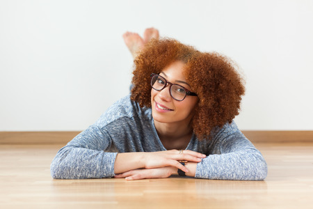 Black African American teenage girl lying down on the wood floorの写真素材