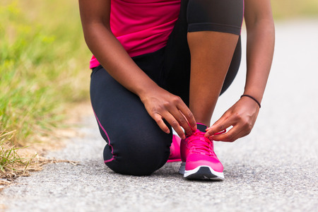 African american woman runner tightening shoe lace - Fitness, people and healthy lifestyleの写真素材