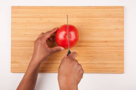 African  American womans hand slicing a tomatoe - Flat layの写真素材