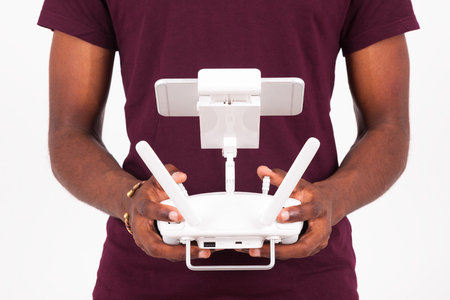 African American young man holding a drone remote control over white background