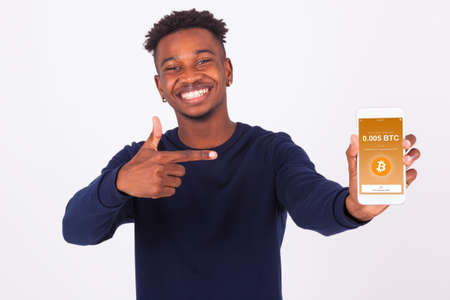 Young African American man pointing his smartphone screen  showing a received crypto currency transaction of bitcoin btc received - Black teenager peopleの写真素材