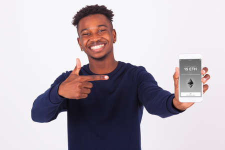 Young African American man pointing his smartphone screen  showing a received crypto currency transaction of ethereum eth received - Black teenager peopleの写真素材