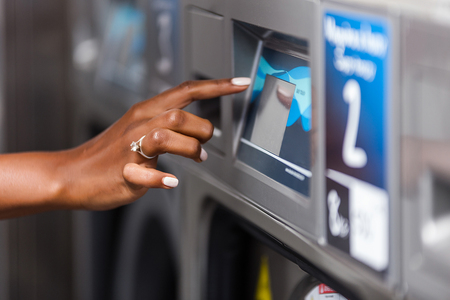 Young black African American woman  hand close up using a washing machine in a laundryの写真素材