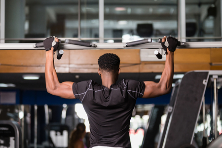 Black African American  young man doing pull up workout at the gym