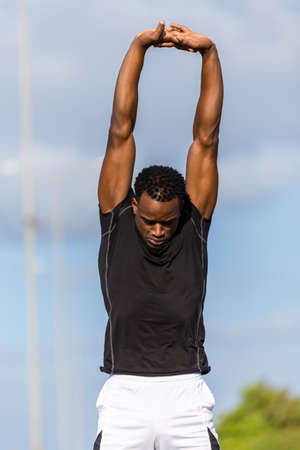 Black african american young man stretching after outdoor joggingの写真素材