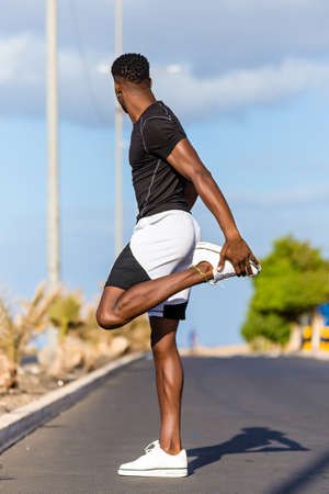 Black african american young man stretching after outdoor joggingの写真素材