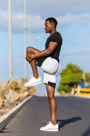 Black african american young man stretching after outdoor joggingの写真素材