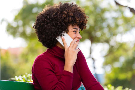 Outdoor portrait of a Young black African American young woman speaking on mobile phoneの写真素材