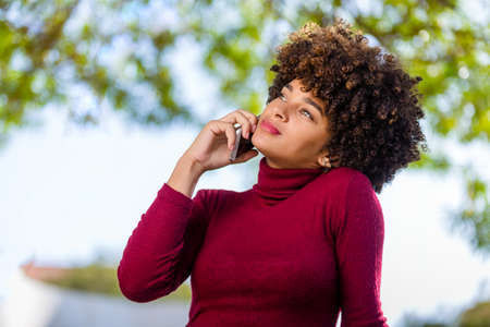 Outdoor portrait of a Young black African American young woman speaking on mobile phoneの写真素材