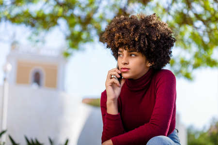 Outdoor portrait of a Young black African American young woman speaking on mobile phoneの写真素材