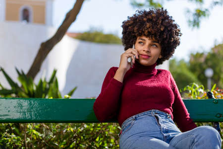 Outdoor portrait of a Young black African American young woman speaking on mobile phoneの写真素材