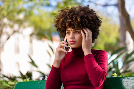 Outdoor portrait of a Young black African American young woman speaking on mobile phoneの写真素材
