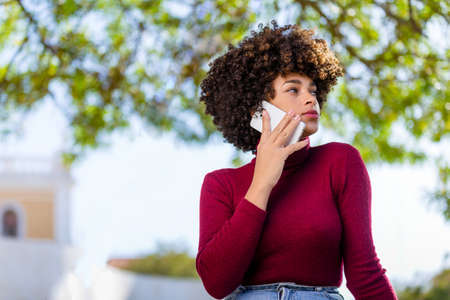 Outdoor portrait of a Young black African American young woman speaking on mobile phoneの写真素材