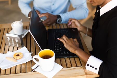 Black African American coworkers doing digital teamwork around a coffee cupの写真素材