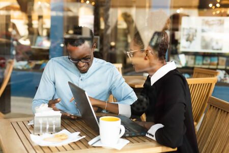 Black African American coworkers doing digital teamwork around a coffee cupの写真素材